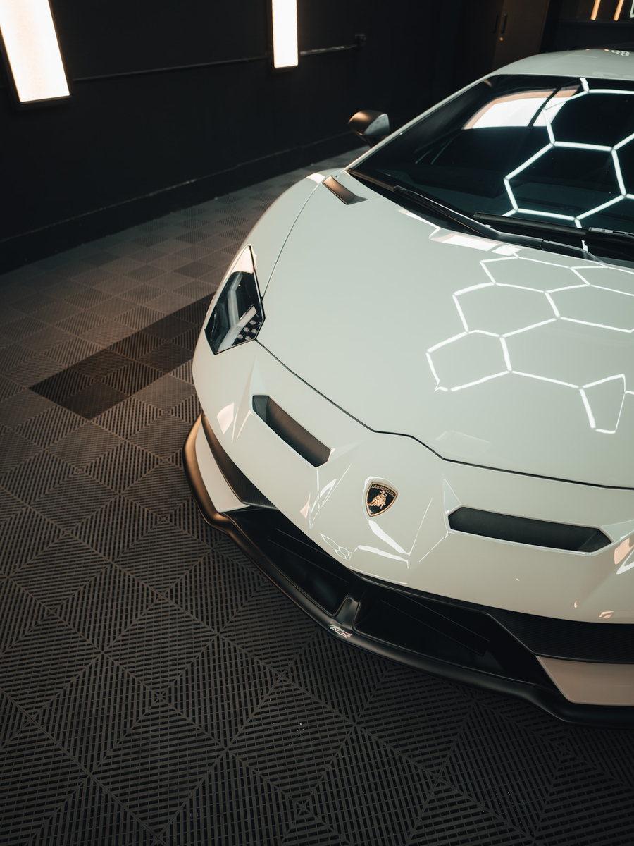 A supercar parked under the lights inside the shop bay.