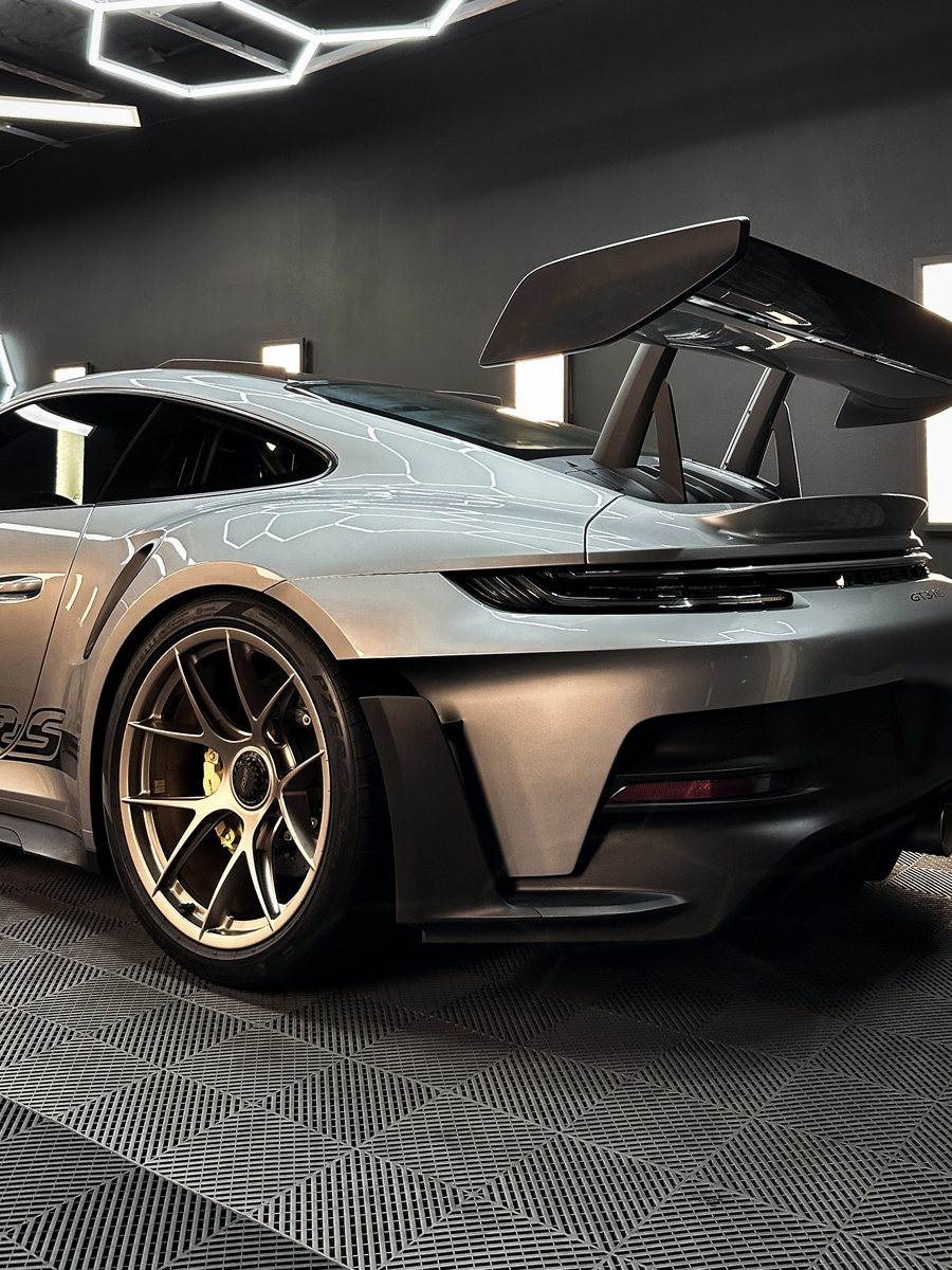 A sports car detailed and parked inside the shop bay.